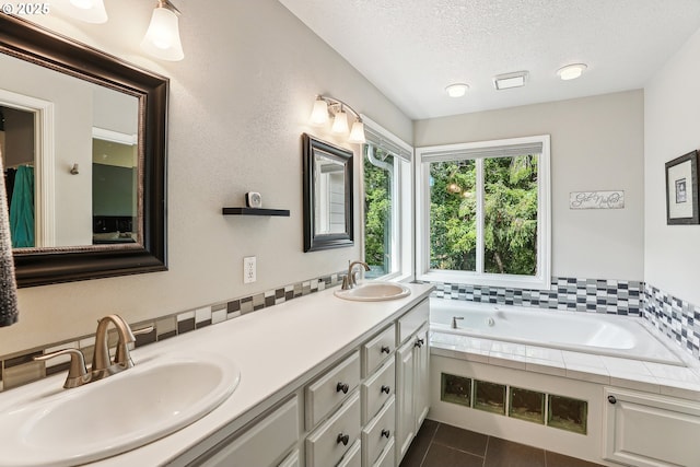 bathroom with a sink, a bath, tile patterned floors, and a textured ceiling