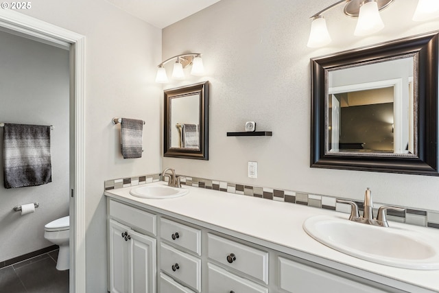 full bathroom with double vanity, toilet, a sink, and tile patterned flooring