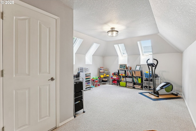 playroom featuring carpet flooring, a textured ceiling, a healthy amount of sunlight, and vaulted ceiling with skylight