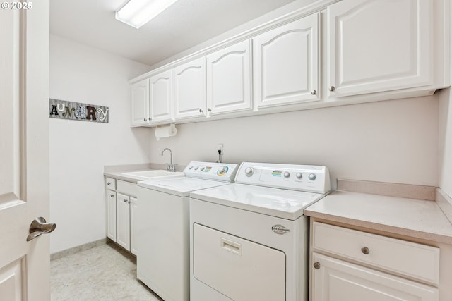 clothes washing area featuring baseboards, a sink, cabinet space, and washing machine and dryer