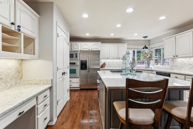 kitchen featuring recessed lighting, a kitchen bar, tasteful backsplash, and stainless steel appliances