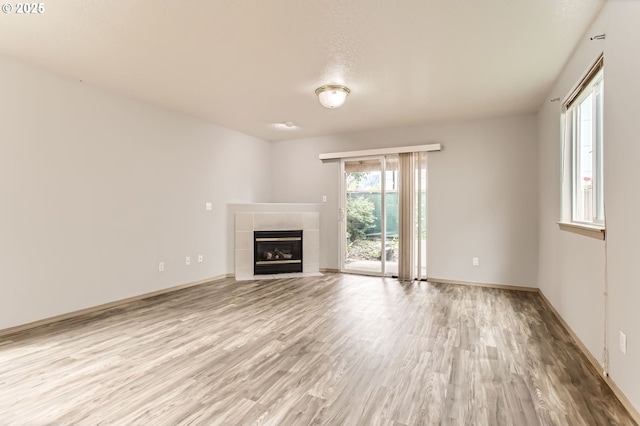 1165 SE 85th Ave, Portland, OR 97216 - unfurnished living room featuring light wood-type flooring and a tiled fireplace