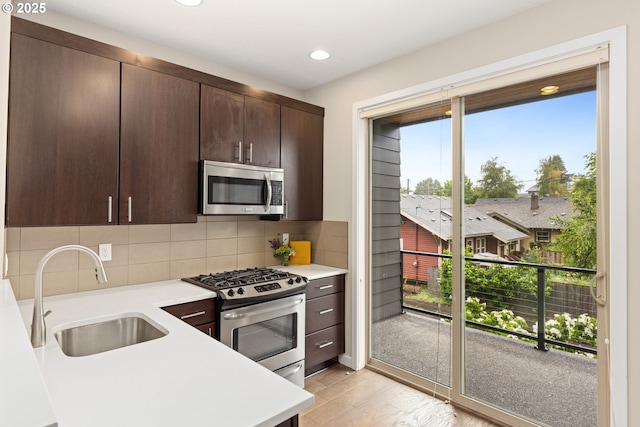 5026 SE Mill St, Portland, OR 97215 - kitchen featuring appliances with stainless steel finishes, a sink, light countertops, dark brown cabinets, and light wood-style flooring