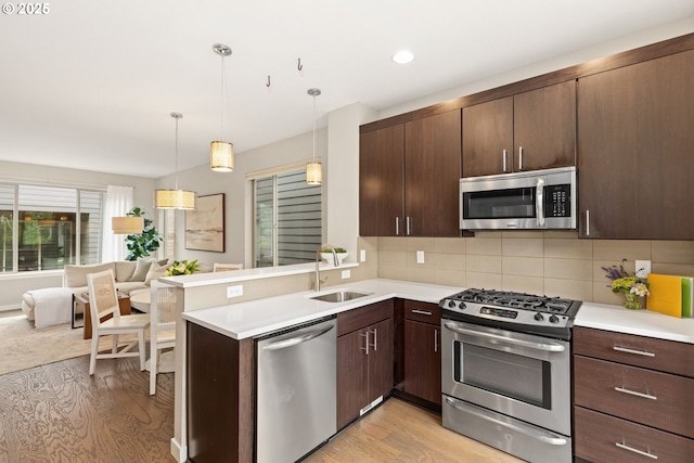5026 SE Mill St, Portland, OR 97215 - kitchen with stainless steel appliances, a sink, light wood-type flooring, open floor plan, and dark brown cabinets