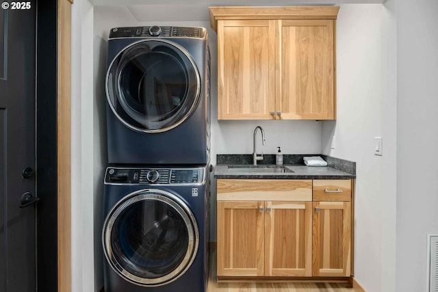 laundry room featuring stacked washing machine and dryer and cabinet space