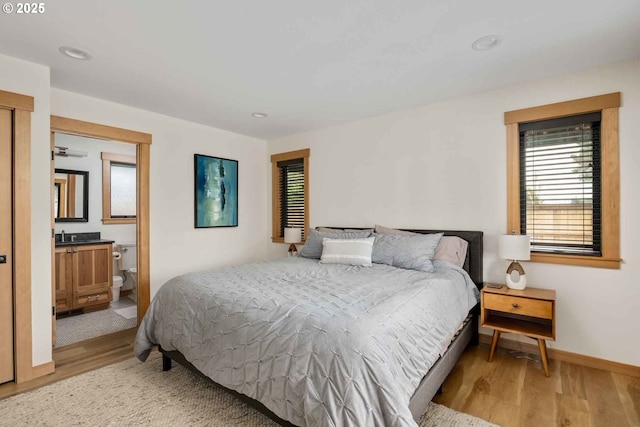 bedroom with light wood finished floors, baseboards, recessed lighting, and ensuite bathroom