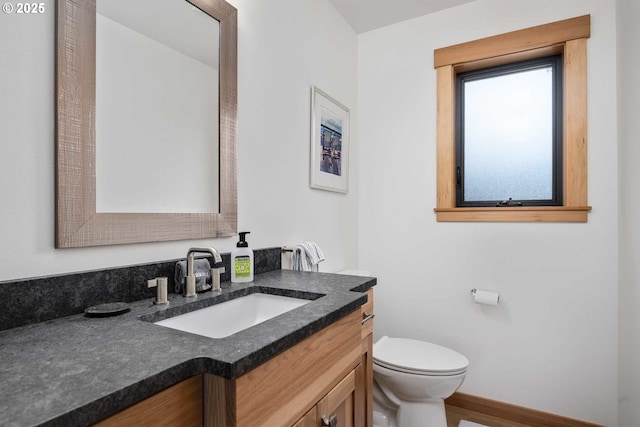 bathroom featuring toilet, vanity, and baseboards