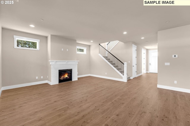 17301 SW Atfalati Ln Unit 38, Sherwood, OR 97140 - unfurnished living room featuring healthy amount of natural light, a glass covered fireplace, wood finished floors, recessed lighting, and stairway