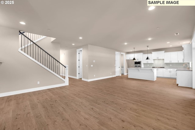 17301 SW Atfalati Ln Unit 38, Sherwood, OR 97140 - unfurnished living room with recessed lighting, light wood-style flooring, and stairway