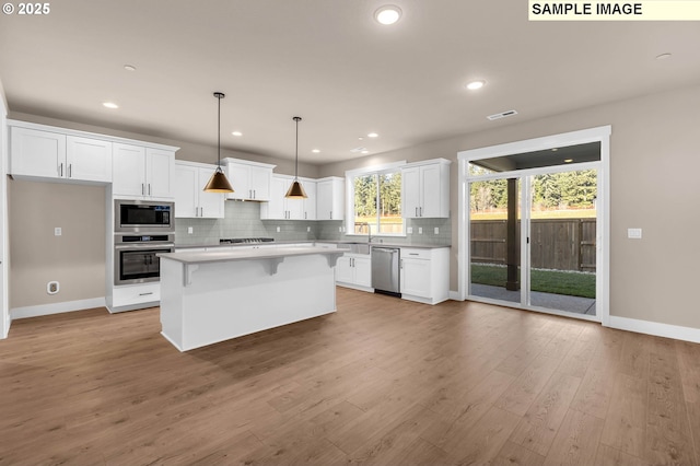 17301 SW Atfalati Ln Unit 38, Sherwood, OR 97140 - kitchen featuring stainless steel appliances, white cabinets, tasteful backsplash, light countertops, and a breakfast bar