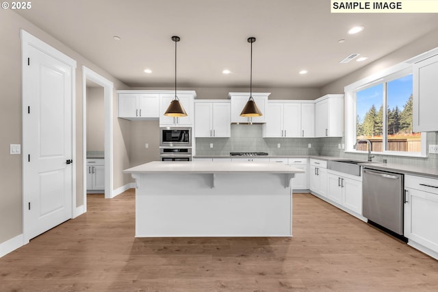 17301 SW Atfalati Ln Unit 38, Sherwood, OR 97140 - kitchen featuring appliances with stainless steel finishes, backsplash, white cabinetry, a kitchen island, and recessed lighting