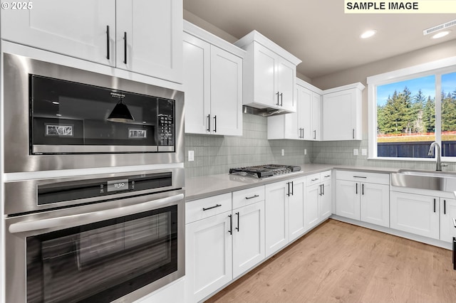 17301 SW Atfalati Ln Unit 38, Sherwood, OR 97140 - kitchen featuring appliances with stainless steel finishes, light countertops, white cabinetry, light wood-type flooring, and tasteful backsplash