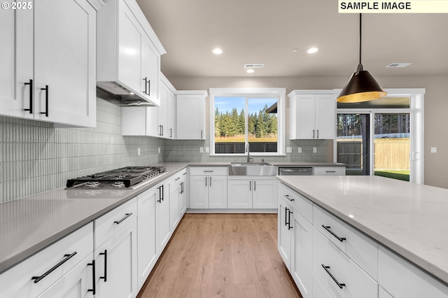 17301 SW Atfalati Ln Unit 38, Sherwood, OR 97140 - kitchen featuring stainless steel gas cooktop, white cabinets, light wood-type flooring, tasteful backsplash, and hanging light fixtures
