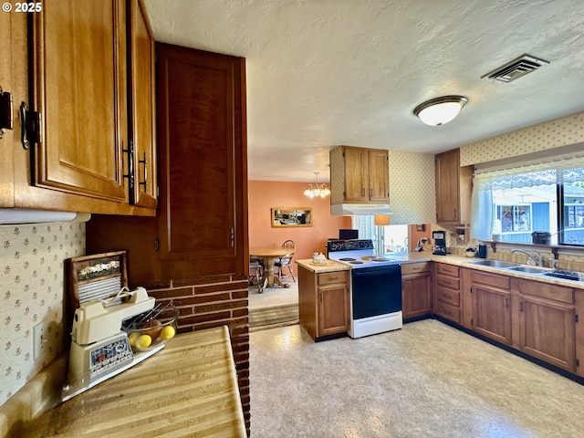 330 Maple St, Brookings, OR 97415 - kitchen with range with electric cooktop, brown cabinetry, under cabinet range hood, light countertops, and a textured ceiling