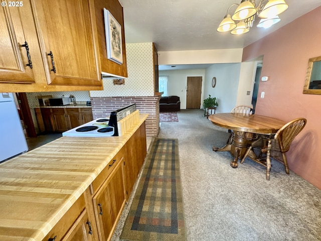 330 Maple St, Brookings, OR 97415 - kitchen with dark carpet, brown cabinets, a chandelier, freestanding refrigerator, and hanging light fixtures