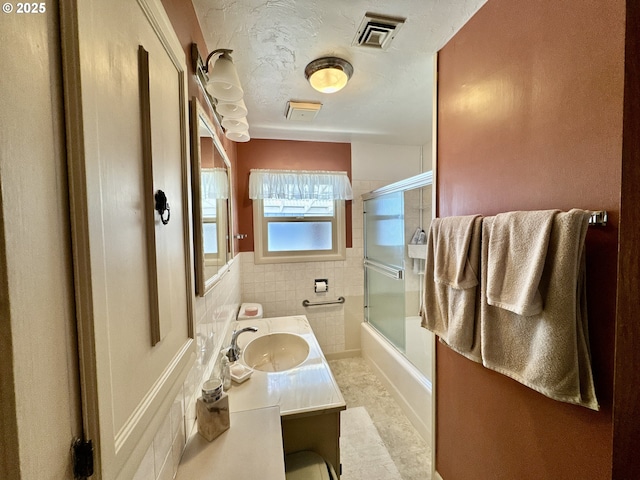 330 Maple St, Brookings, OR 97415 - full bathroom featuring vanity, shower / bath combination with glass door, tile walls, and a wainscoted wall