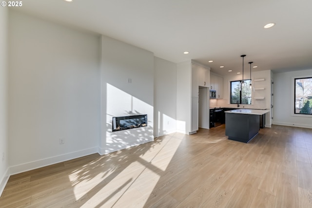 kitchen featuring pendant lighting, white cabinetry, a kitchen island, and light wood-type flooring