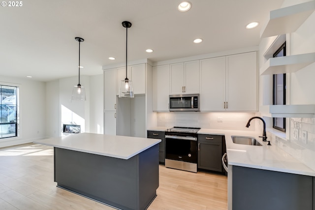 kitchen featuring sink, decorative light fixtures, a center island, appliances with stainless steel finishes, and white cabinets