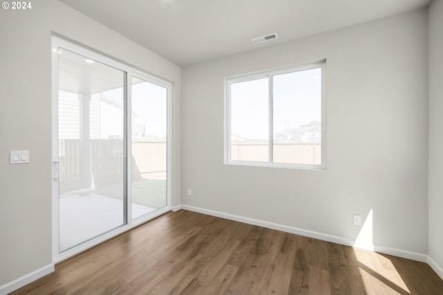 empty room featuring visible vents, baseboards, and wood finished floors