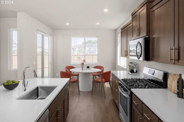 kitchen featuring wood finished floors, stainless steel appliances, a sink, and light countertops