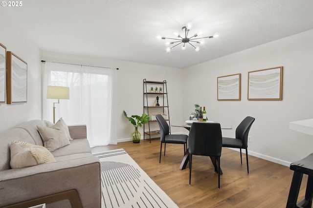 dining space featuring light wood-style flooring, a notable chandelier, and baseboards