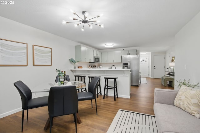 dining area with a chandelier, light wood finished floors, and baseboards