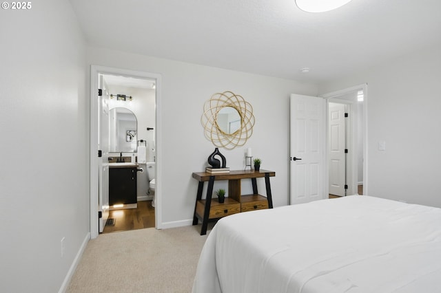 carpeted bedroom featuring arched walkways, a sink, baseboards, and connected bathroom