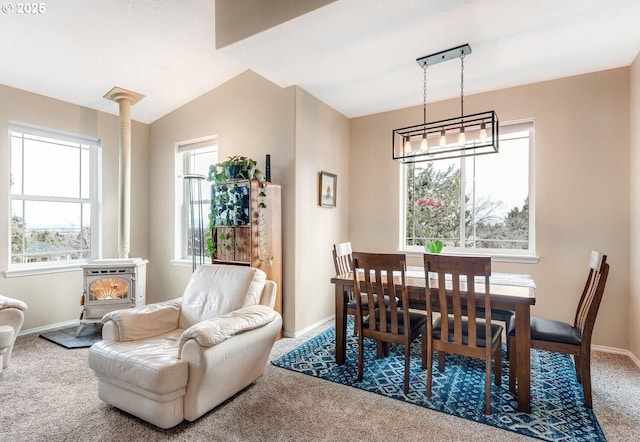 dining area featuring vaulted ceiling, carpet flooring, a wood stove, and baseboards