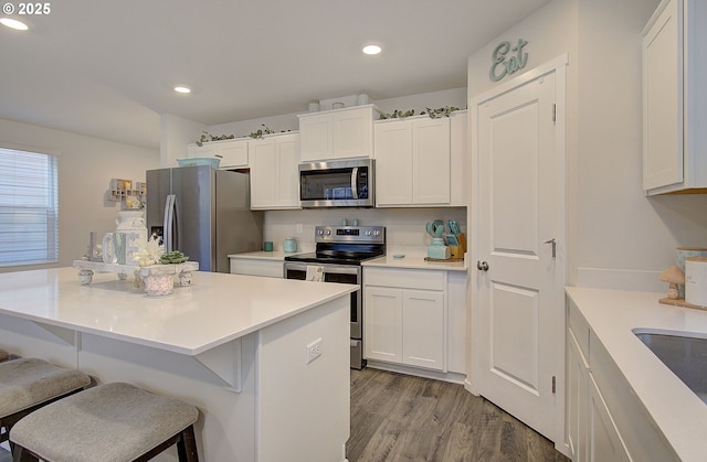 kitchen featuring light wood-type flooring, a breakfast bar, white cabinets, and appliances with stainless steel finishes