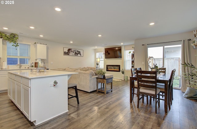 kitchen with white cabinetry, a breakfast bar area, a kitchen island, and hardwood / wood-style flooring