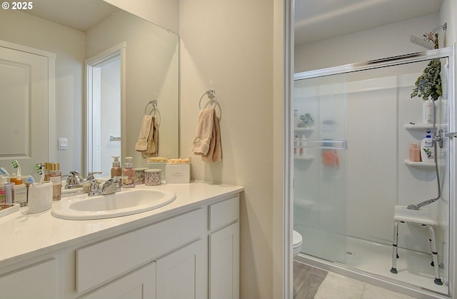 bathroom with vanity, wood-type flooring, an enclosed shower, and toilet