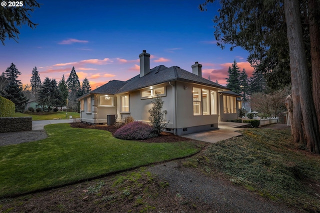 property exterior at dusk featuring a yard, central AC, and a patio area