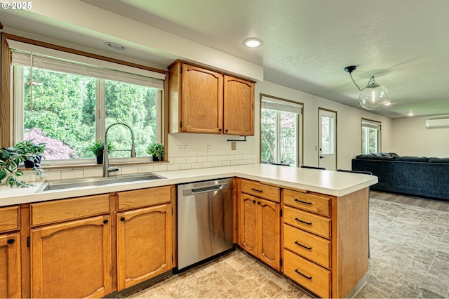 kitchen with a sink, dishwasher, light countertops, an AC wall unit, and a peninsula