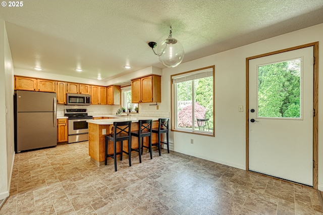 kitchen featuring light countertops, stone finish flooring, appliances with stainless steel finishes, and a peninsula