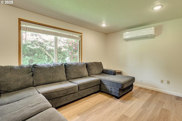 living area with a textured ceiling, light wood-type flooring, a wall mounted air conditioner, baseboards, and recessed lighting