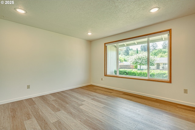 empty room featuring baseboards, recessed lighting, a textured ceiling, and light wood-style flooring