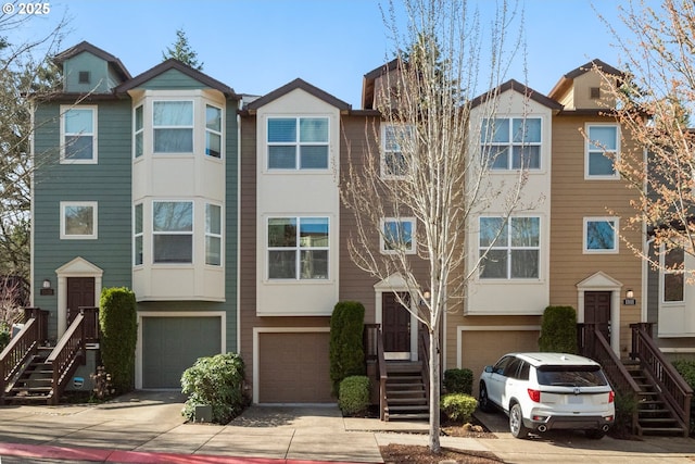 multi unit property featuring a garage, stairs, and concrete driveway