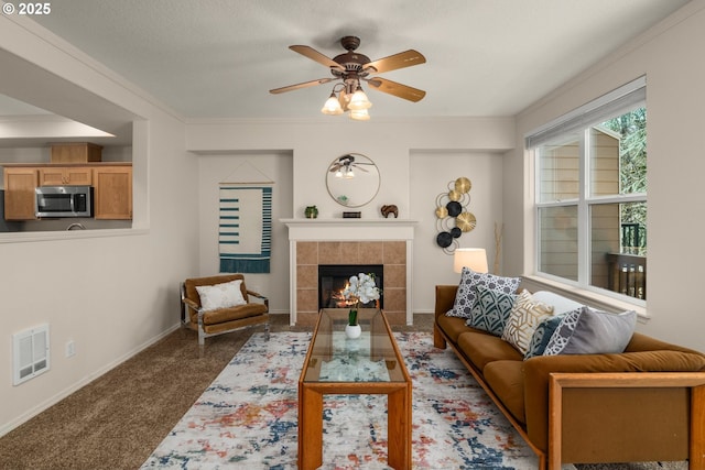 living room featuring carpet floors, a fireplace, visible vents, and crown molding