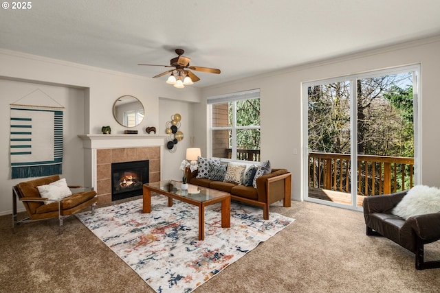 living area with a ceiling fan, a fireplace, ornamental molding, and carpet flooring