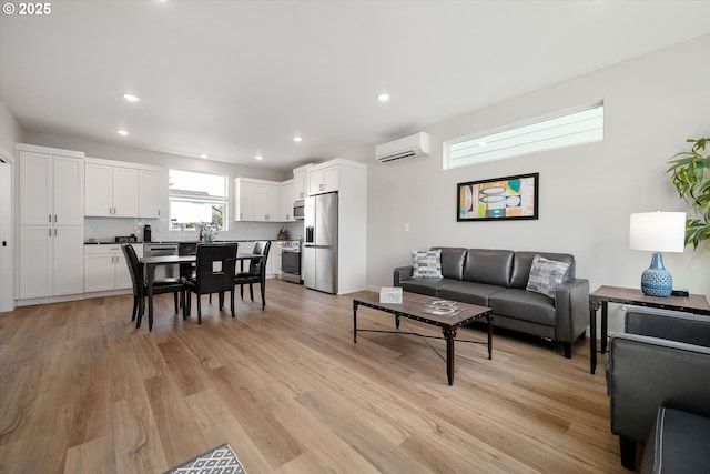 living area with light wood-style flooring, an AC wall unit, and recessed lighting