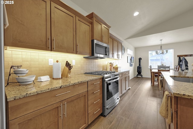 760 S 52nd St, Springfield, OR 97478 - kitchen featuring appliances with stainless steel finishes, lofted ceiling, wood finished floors, brown cabinets, and tasteful backsplash