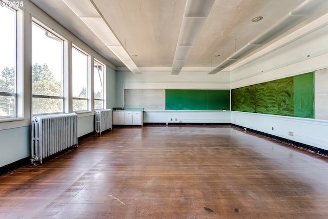 unfurnished room with radiator, dark wood-type flooring, and beam ceiling