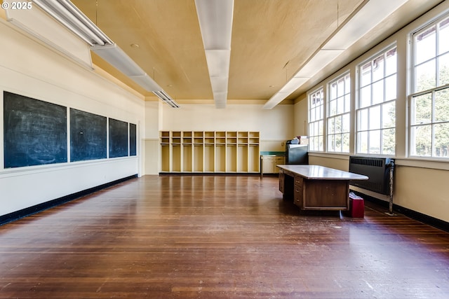 interior space featuring radiator, dark wood-type flooring, and beam ceiling