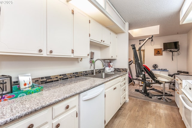 kitchen with light wood-style flooring, a sink, a textured ceiling, white cabinetry, and white dishwasher