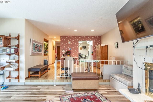 living room featuring a textured ceiling, wood finished floors, recessed lighting, wallpapered walls, and baseboards