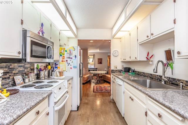 kitchen featuring backsplash, light wood-style flooring, white appliances, and a sink