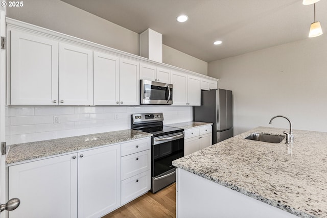1502 Timothy St, Philomath, OR 97370 - kitchen featuring appliances with stainless steel finishes, a sink, white cabinets, light wood-style floors, and backsplash