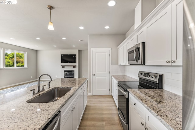 1502 Timothy St, Philomath, OR 97370 - kitchen featuring appliances with stainless steel finishes, a sink, white cabinetry, decorative backsplash, and light wood finished floors
