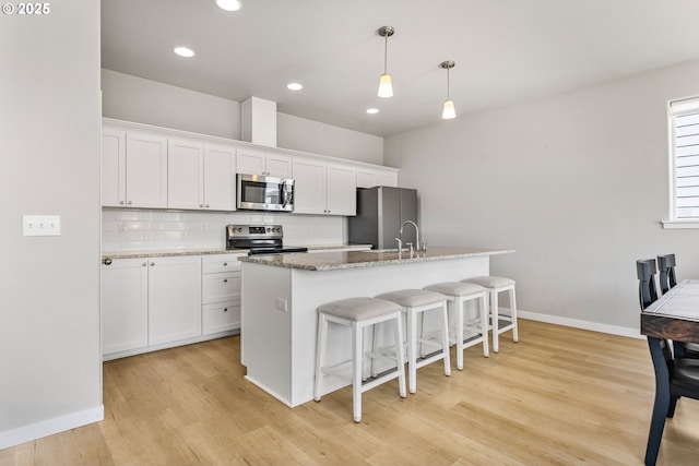 1502 Timothy St, Philomath, OR 97370 - kitchen with appliances with stainless steel finishes, light wood-style floors, backsplash, a breakfast bar, and baseboards