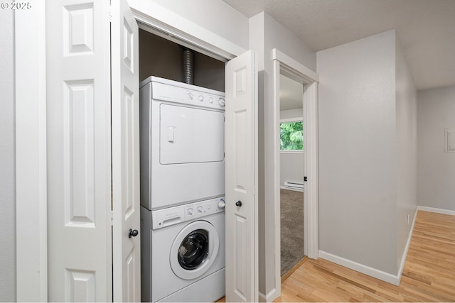 3925 SW Multnomah Blvd Unit 204, Portland, OR 97219 - laundry room with stacked washer and clothes dryer, light wood finished floors, a baseboard radiator, and baseboards